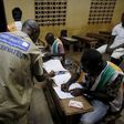 Election observer stands near polling workers as they count the ballots at a polling station in Yamoussoukro, Ivory Coast October 25, 2015 REUTERS/ Thierry Gouegnon