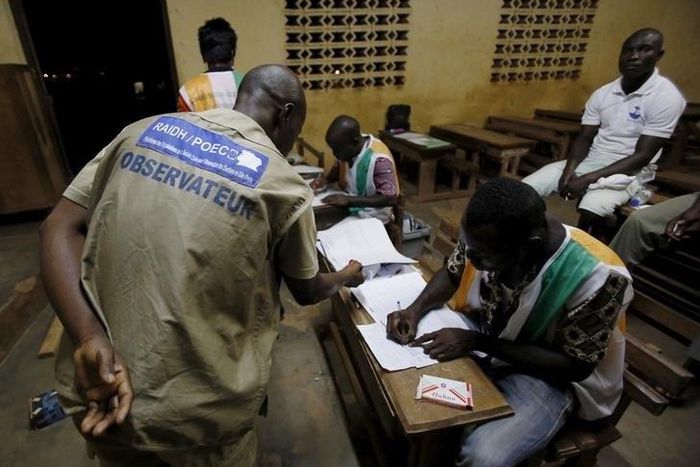 Election observer stands near polling workers as they count the ballots at a polling station in Yamoussoukro, Ivory Coast October 25, 2015 REUTERS/ Thierry Gouegnon