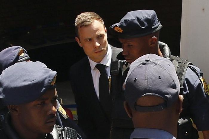 South African Olympic and Paralympic sprinter Oscar Pistorius (C) is escorted to a police van after his sentencing at the North Gauteng High Court in Pretoria October 21, 2014. REUTERS/Siphiwe Sibeko/Files