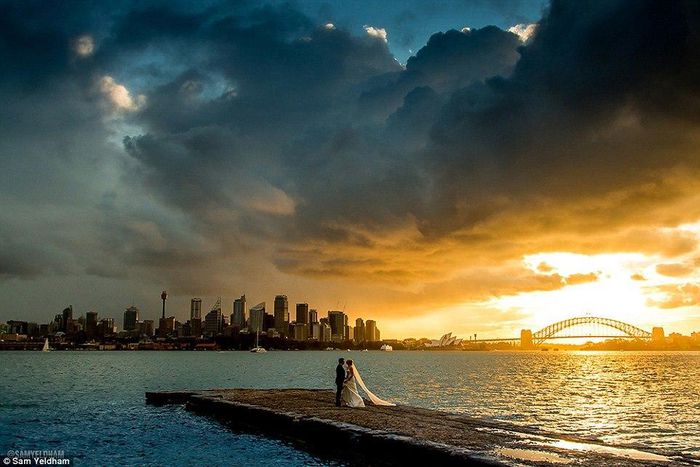 Photographer Sam Yeldham captured the clouds parting for a picture perfect minute behind the happy newlyweds (pictured)