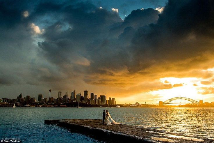 Photographer Sam Yeldham captured the clouds parting for a picture perfect minute behind the happy newlyweds (pictured)