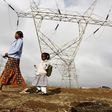 A woman walks her child to school past high voltage electrical pylons on the outskirts of Kenya's capital Nairobi, March 14, 2011.   REUTERS/Thomas Mukoya
