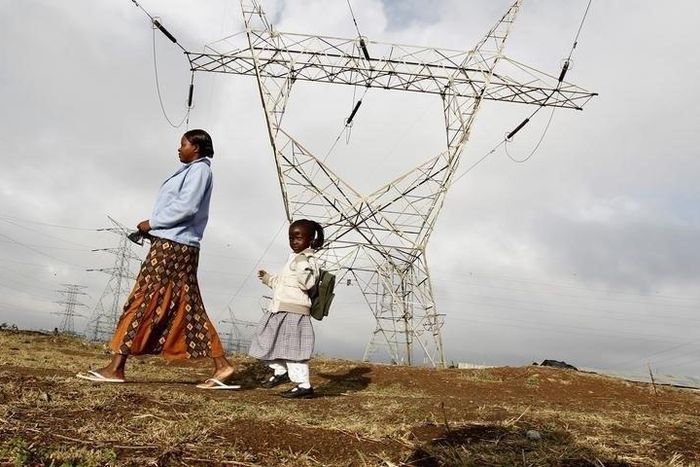 A woman walks her child to school past high voltage electrical pylons on the outskirts of Kenya's capital Nairobi, March 14, 2011.   REUTERS/Thomas Mukoya