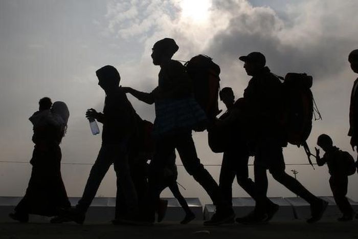 Migrants are silhouetted against the sky as they make their way to board buses in Nickelsdorf, Austria, October 6, 2015. REUTERS/Leonhard Foeger