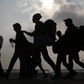 Migrants are silhouetted against the sky as they make their way to board buses in Nickelsdorf, Austria, October 6, 2015. REUTERS/Leonhard Foeger