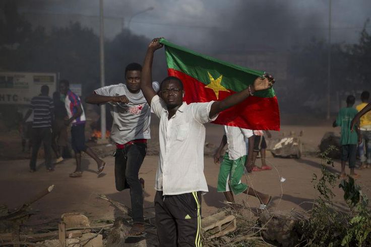 An anti-coup protester holds a Burkinabe flag in Ouagadougou, Burkina Faso, September 18, 2015. Leaders of a coup in Burkina Faso said on Friday they had freed the president and reopened borders, in an apparent olive branch to mediators and protesters ...