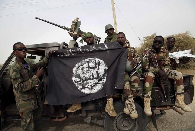 Nigerian soldiers hold up a Boko Haram flag that they had seized in the recently retaken town of Damasak, Nigeria, March 18, 2015.
