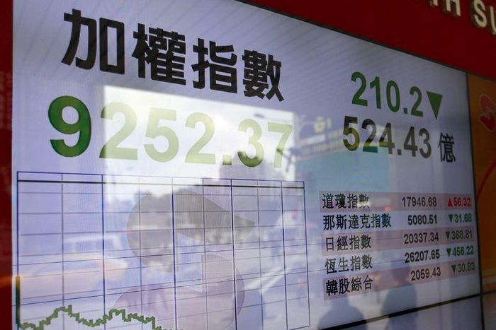People walk past  in front of a monitor showing stock market prices in Taipei, Taiwan, June 29, 2015.    REUTERS/Pichi Chuang