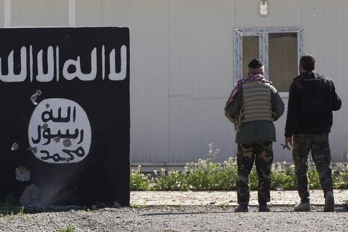 Shi'ite fighters stand near a wall painted with the black flag commonly used by Islamic State militants in the town of Tal Ksaiba, near the town of al-Alam March 7, 2015. REUTERS/Thaier Al-Sudani