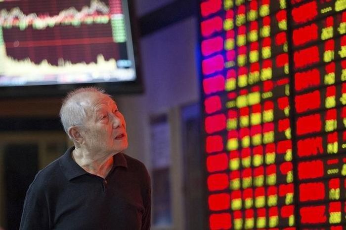 An investor walks past an electronic board showing stock information at a brokerage house in Nanjing, Jiangsu province, China, September 22, 2015. REUTERS/Stringer