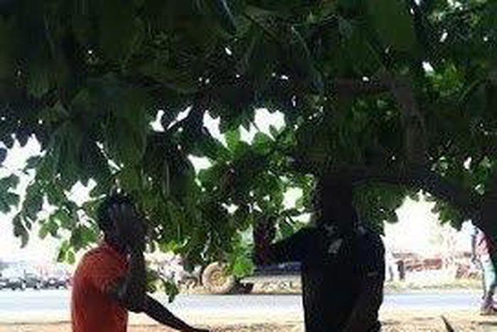 The brutalized okada man hanging on to the policeman's pants