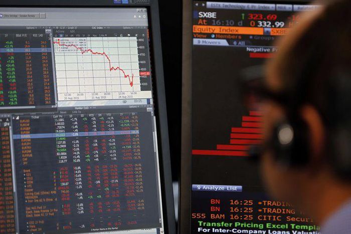 A sales manager sits near a screen with a graphic that shows a decline in value of French CAC 40 stocks at Allianz Global Investors in Paris, France, August 24, 2015. REUTERS/Regis Duvignau