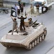 Militant Islamist fighters hold the flag of Islamic State (IS) while taking part in a military parade along the streets of northern Raqqa province in this June 30, 2014