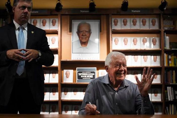 Former President Jimmy Carter waves to the crowd as he signs his new book titled A Full Life: Reflections at 90.
