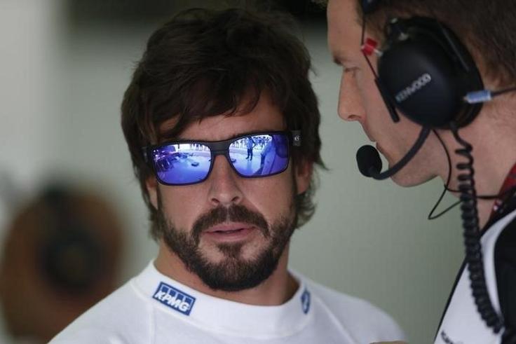 McLaren's Fernando Alonso (L) speaks to a crew member before practice for the Malaysian Grand Prix. Reuters / Olivia Harris