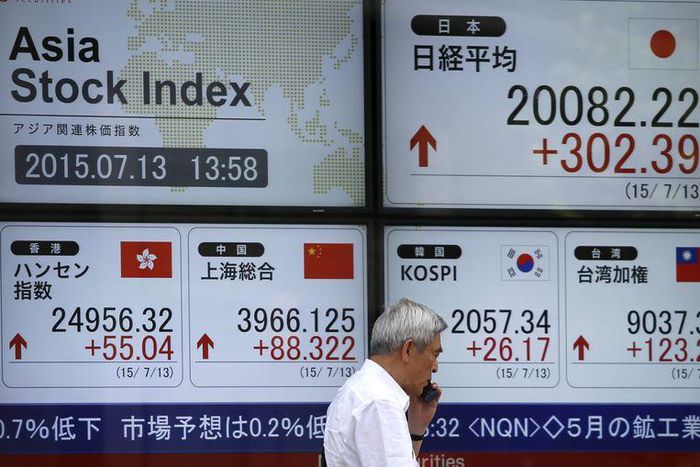 A man walks past in front of an electronic board displaying various Asian countries' stock price index outside a brokerage in Tokyo July 13, 2015.   REUTERS/Issei Kato