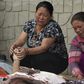 Grieving women hold the hands of relatives as they lie beneath a thin white sheet in the city of Kathmandu.