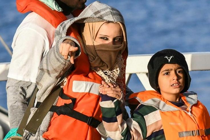 A mother and a child, part of a group of 49 migrants, react as they disembark from one of Malta's AFM Protector-class coastal patrol boats on January 9 after being transfered from the Dutch-flagged rescue Vessel "Sea Watch 3" (unseen) to Haywharf in Va...