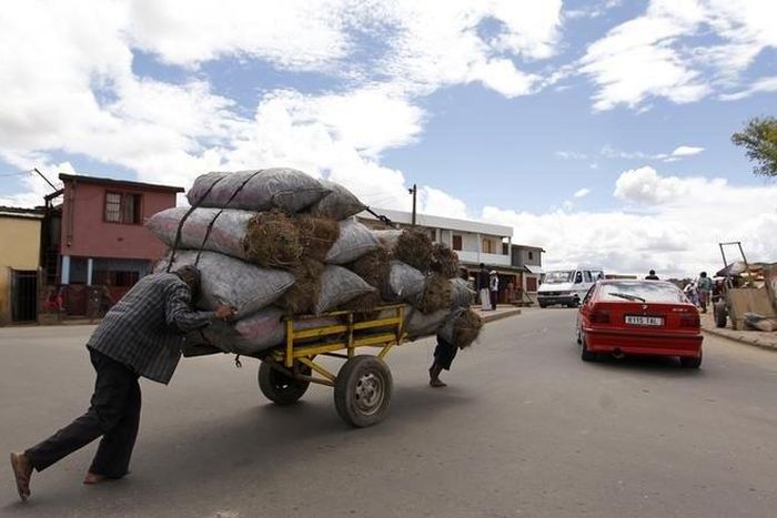 Men push charcoal for sale on a handcart along the streets of Madagascar's capital Antananarivo, December 22, 2013.   REUTERS/Thomas Mukoya