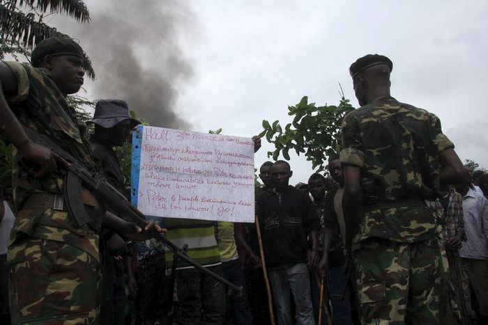 Soldiers, standing near a sign with a message against Burundian President Pierre Nkurunziza's plan to run for a third term in office, talk to protesters as they barricade a road in Bujumbura, May 8, 2015. REUTERS/Jean Pierre Aime Harerimana