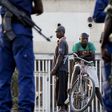 Residents look on as police and soldiers guard a voting station in Burundi's capital Bujumbura during the country's presidential elections, July 21, 2015.   REUTERS/Mike Hutchings