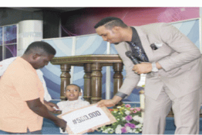 Pastor Chris Okafor presenting little Oluwanimilo Afolabi with the sum of N500,000