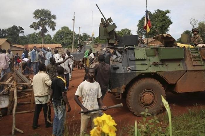 Men stand facing French soldiers as they block a road which French army vehicles were travelling on, during a protest in Bambari May 22, 2014. REUTERS/Goran Tomasevic