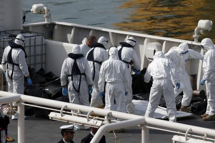 Italian coastguard and Armed Forces of Malta personnel in protective clothing stand near the bodies of dead immigrants on the ship Bruno Gregoretti in Senglea in Valletta's Grand Harbour, April 20, 2015. REUTERS/Darrin Zammit Lupi
