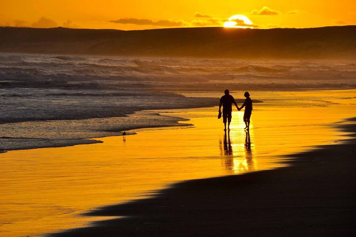 Couple taking a romantic walk on the beach at Sunset