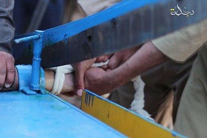 The accused thief's right hand is locked in a blue vice and hacked off with what appears to be an industrial-sized paper guillotine