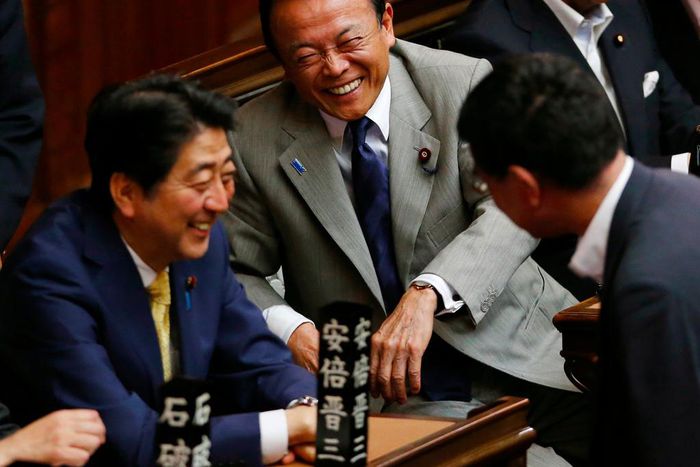 Financial Minister Taro Aso, center, and Japanese Prime Minister Shinzo Abe, left, share a light moment during a plenary session at the lower house in Tokyo, Thursday, July 16, 2015.