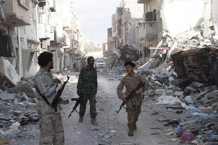 Members of Libyan pro-government forces, backed by the locals, walk with weapons during clashes in the streets with Shura Council of Libyan Revolutionaries, an alliance of former anti-Gaddafi rebels who have joined forces with Islamist group Ansar al-S...