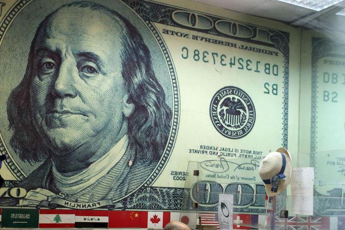 A mirror reflection shows an employee working in a foreign exchange office in central Cairo April 16, 2015.    REUTERS/Asmaa Waguih