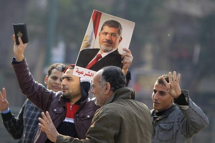 Supporters of the Muslim Brotherhood and ousted Egyptian President Mohamed Mursi hold a copy of the Koran and Mursi's picture at Talaat Harb Square, in Cairo, January 25, 2015. REUTERS/Mohamed Abd El Ghany