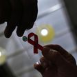 A nurse (L) hands out a red ribbon to a woman, to mark World Aids Day, at the entrance of Emilio Ribas Hospital, in Sao Paulo December 1, 2014. REUTERS/Nacho Doce
