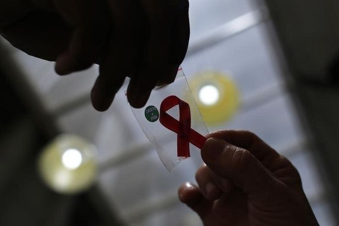A nurse (L) hands out a red ribbon to a woman, to mark World Aids Day, at the entrance of Emilio Ribas Hospital, in Sao Paulo December 1, 2014. REUTERS/Nacho Doce