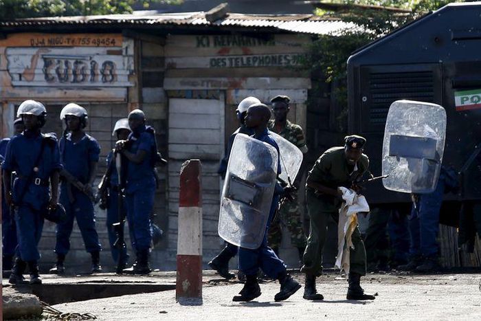 A policeman carries a shield as a soldiers walk behind while protesters throw stones during a protest against president Pierre Nkurunziza in Bujumbura, Burundi, May 10. 2015.    REUTERS/Goran Tomasevic