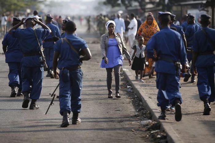 A woman passes by policemen during a protest against Burundi President Pierre Nkurunziza and his bid for a third term in Bujumbura, Burundi, June 2, 2015. REUTERS/Goran Tomasevic