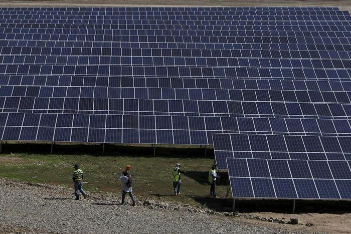 Workers walk past newly installed solar panels at the Honduran Solar Energy Company SA (COHESSA) and Solar Power SA (Soupy) solar power plant in Nacaome, Honduras, May 12, 2015.  REUTERS/Jorge Cabrera