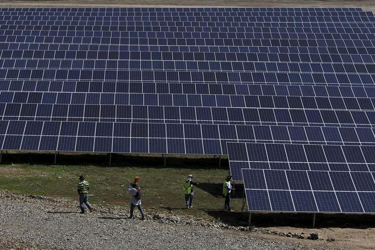 Workers walk past newly installed solar panels at the Honduran Solar Energy Company SA (COHESSA) and Solar Power SA (Soupy) solar power plant in Nacaome, Honduras, May 12, 2015.  REUTERS/Jorge Cabrera