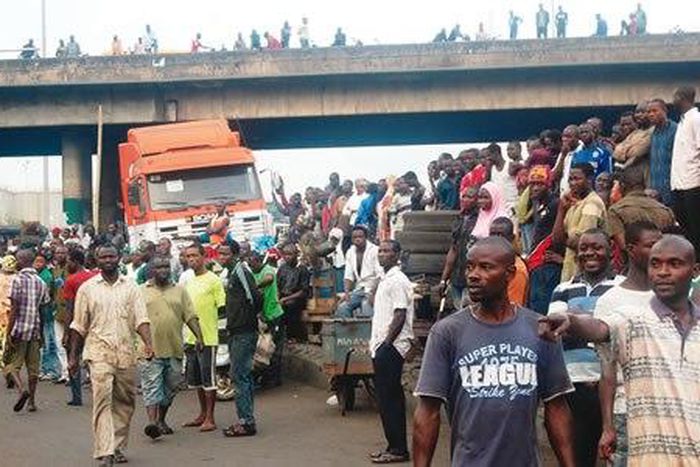 Crowd gathers near a bridge in Ijora Badia during a battle between police and robbers