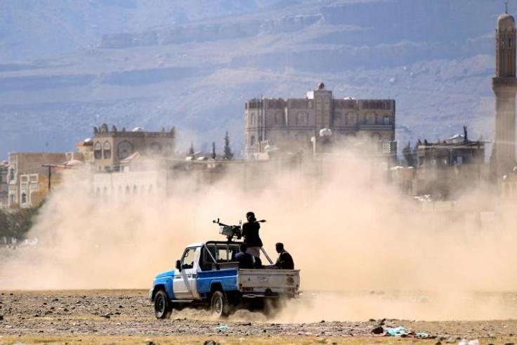 Yemeni men stand at the back of an armed pick-up as people in the capital Sanaa show their support for the Shiite Huthi rebel movement in December 2018
