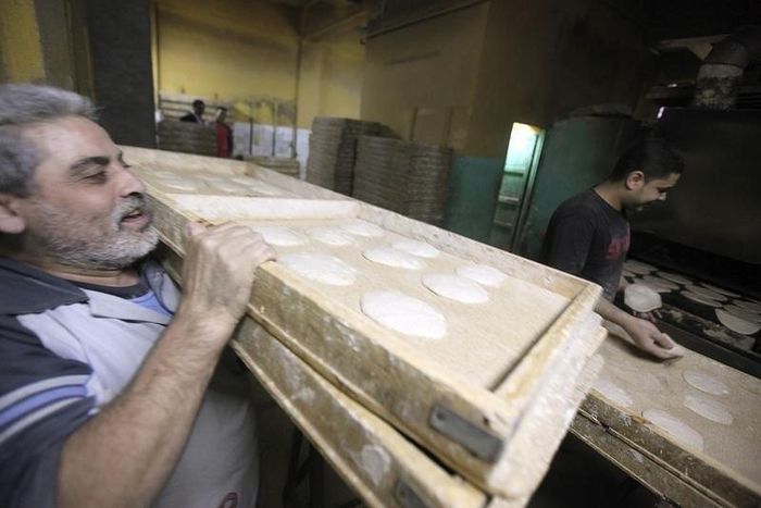 A worker carries trays of bread to be baked in an oven at a bakery in Cairo March 17, 2013. REUTERS/Mohamed Abd El Ghany