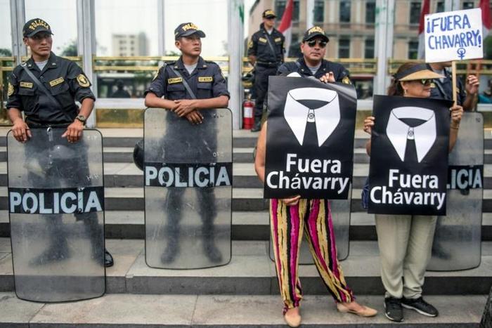 People hold up posters saying 'Chavarry Out' during a protest against Peru's attorney general in Lima on January 8, 2019, before he stepped down