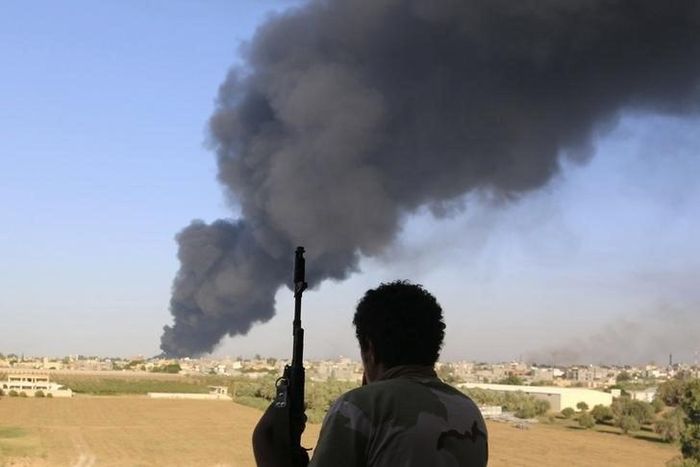 A fighter from Zintan brigade watches as smoke rises after rockets fired by one of Libya's militias struck and ignited a fuel tank in Tripoli, in a file photo. REUTERS/Hani Amara