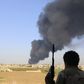 A fighter from Zintan brigade watches as smoke rises after rockets fired by one of Libya's militias struck and ignited a fuel tank in Tripoli, in a file photo. REUTERS/Hani Amara