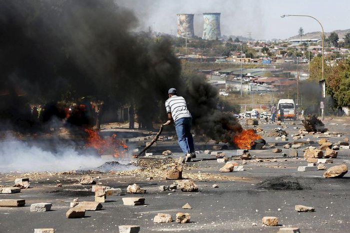 A protester sets tyres alight while protesting against what they called the unaffordable electricity prices, in Soweto May 6, 2015. South African police fired rubber bullets on Wednesday to disperse angry demonstrators who set tyres alight while protes...