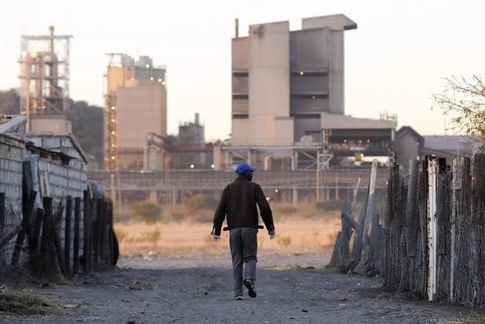 A township resident walks past Lonmin's Marikana platinum mine, in a file photo. REUTERS/Skyler Reid