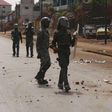 Security forces walk down a street filled with debris after protests in Conakry, Guinea, May 7, 2015. Youths in Guinea's capital blocked roads with burning tyres and clashed with security forces on Thursday, raising pressure on President Alpha Conde ah...