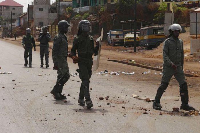 Security forces walk down a street filled with debris after protests in Conakry, Guinea, May 7, 2015. Youths in Guinea's capital blocked roads with burning tyres and clashed with security forces on Thursday, raising pressure on President Alpha Conde ah...